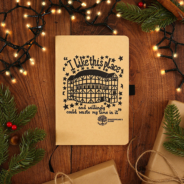 Notebook with Shakespeare quote on a wooden surface with Christmas decorations
