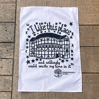 White tea towel with black text and graphic on a wooden surface