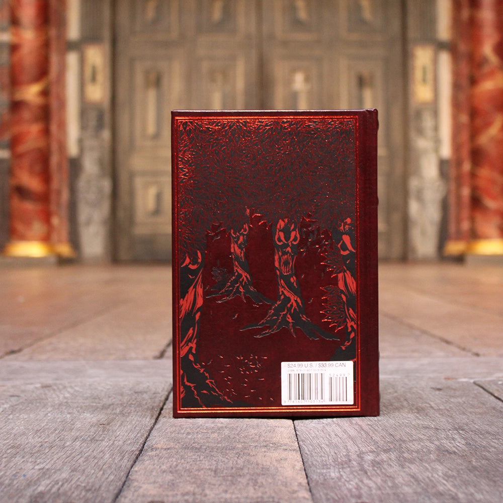 
                  
                    Red leatherbound book with gold script writing and etched forest motif
                  
                