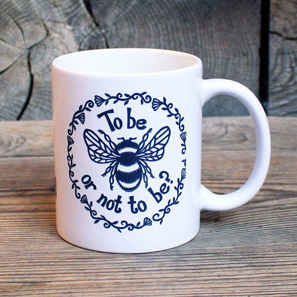 white ceramic mug with a black print of a bee and a quote