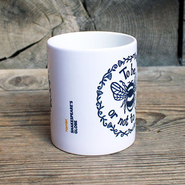 white ceramic mug with a black print of a bee and a quote
