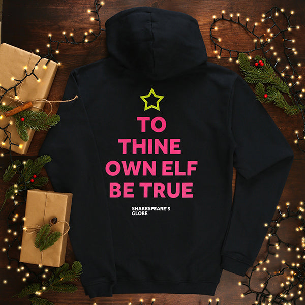 Navy blue hoodie with 'To Thine Own Elf Be True' text on a wooden surface with Christmas decorations.