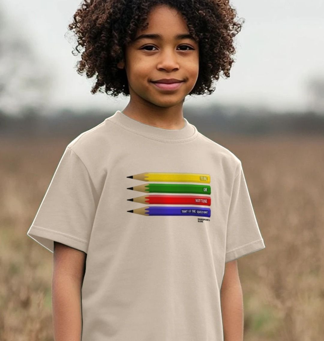 Beige children's t-shirt with centre front graphic of 4 pencils, one on top of the other yellow, green, red, blue with white graphic text on each one