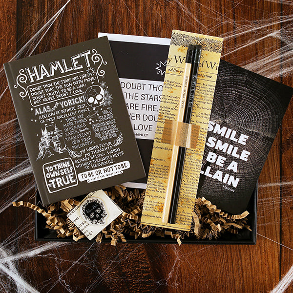 Open black card box with black quote print, black quote card, nude and black pencils with stamped quotes, black quote hardback notebook, and black skull pin badge