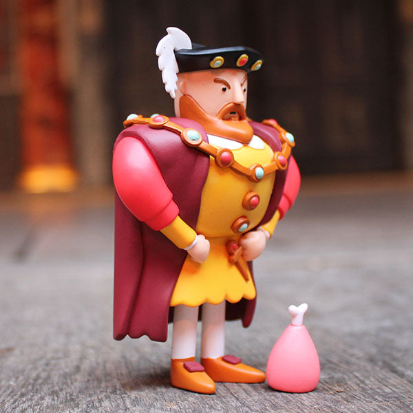 Toy figure of a character in regal attire with a pink object on a textured surface