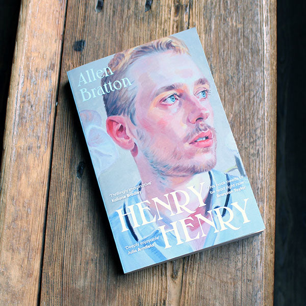 Pale blue paperback book with a portrait of a blonde haired man with blue eyes and white text overlayed