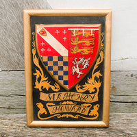 Wooden plaque with a coat of arms and text 'Sir Henry Howard' on a wooden surface