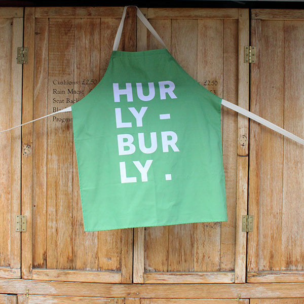 Pale green cotton apron with natural cotton straps, featuring white typographic text