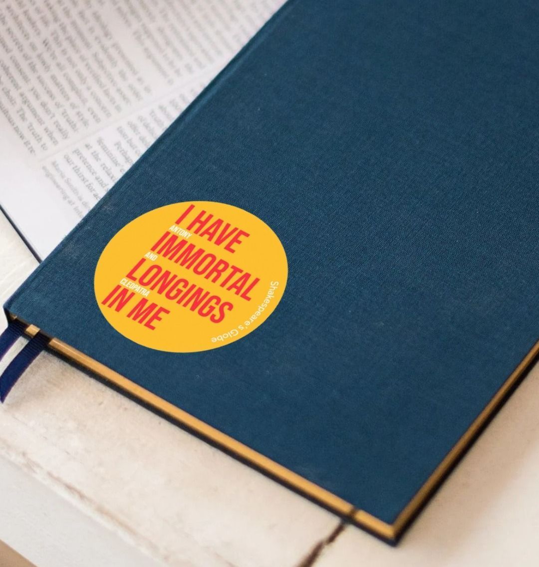 Yellow circular sticker with red and white graphic text on it, stuck to a notebook with pens sitting aside