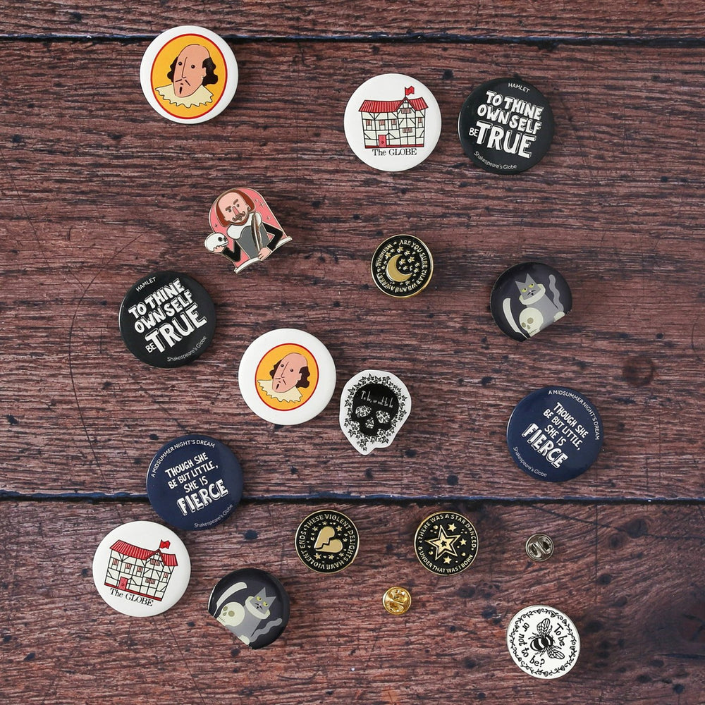 Selection of pin badges and button badges sitting face up on wood panel floor