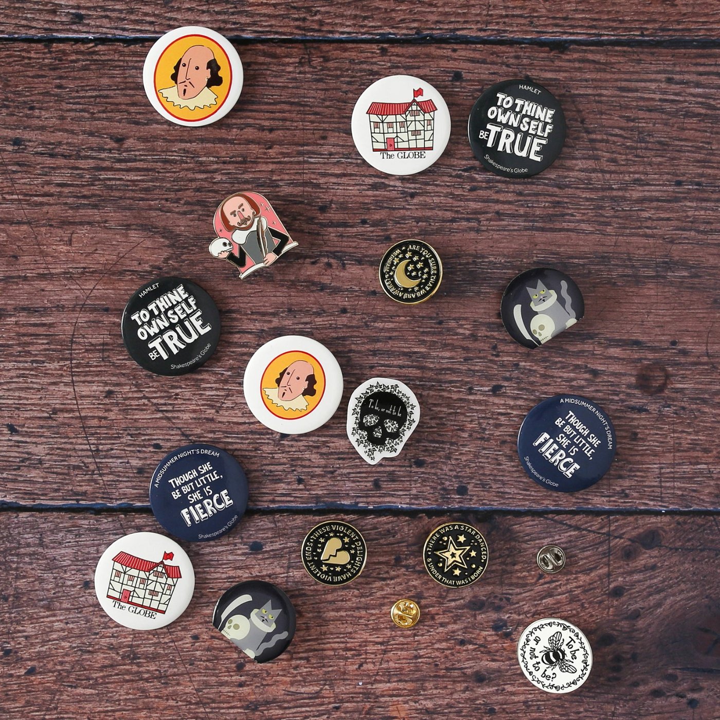 Selection of pin badges and button badges sitting face up on wood panel floor