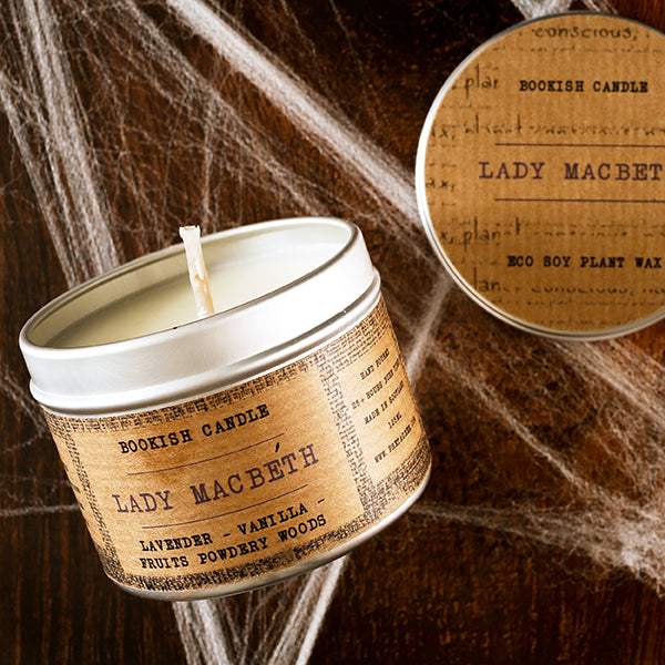 Candle in a tin labeled 'Lady Macbeth' with spider webs in the background