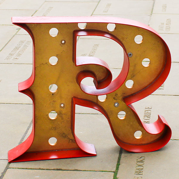 Vintage-style letter 'R' with a red border on a light stone background
