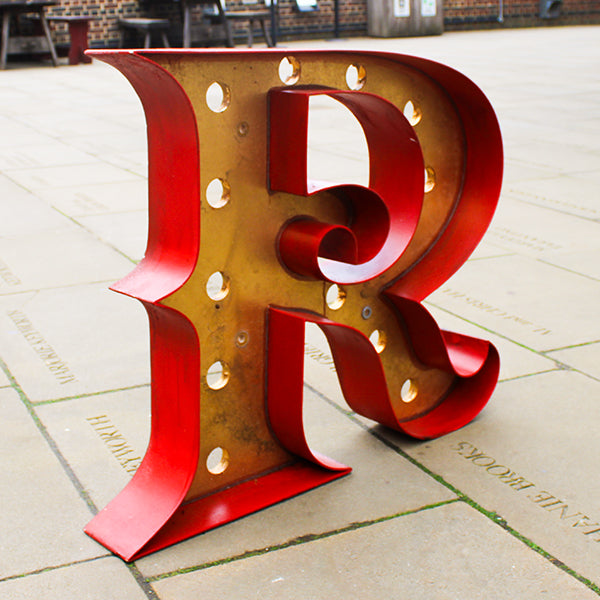 Red wooden letter 'R' on a stone pavement