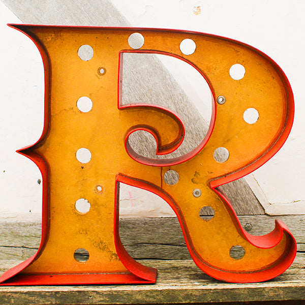 Vintage-style letter 'R' with a rustic design on a wooden surface