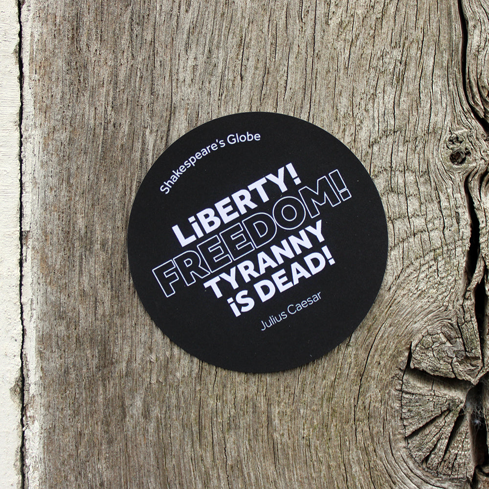 Black circular sticker with white graphic text, stuck on wood