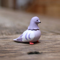 Purple and white pigeon figurine on a wooden surface
