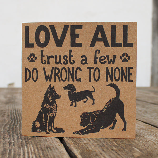 Card with text 'Love all, trust a few, do wrong to none' and dog illustrations on a wooden surface.