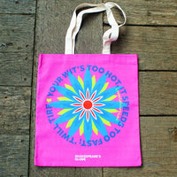 Pink tote bag with colorful design and text on a wooden surface