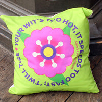 Bright green pillow with a colourful flower design and text on a wooden surface.