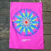bright pink tea towel printed with a large blue flower on a wooden surface
