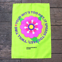 bright green tea towel printed with a large pink flower on a wooden surface
