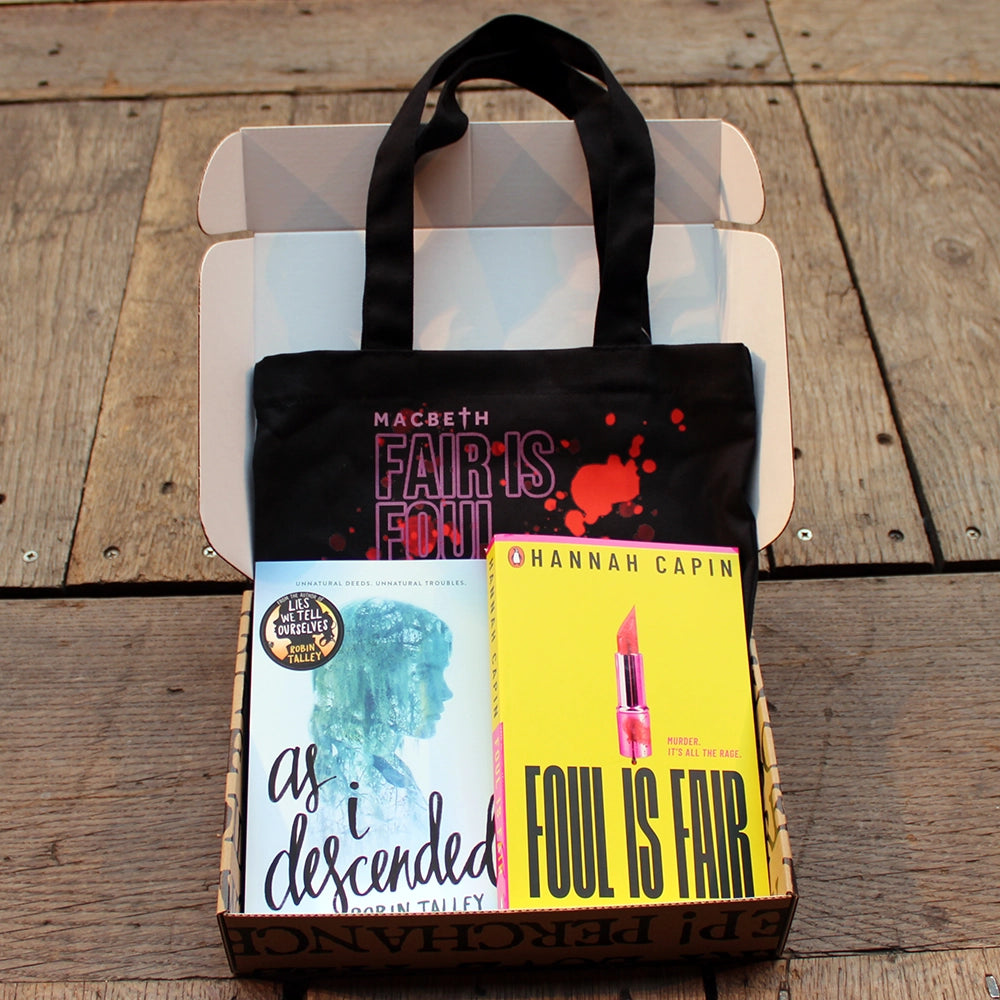 
                  
                    Kraft book box with all over block print, filled with two paperback books, 1 pale blue, 1 bright yellow, and a black book sized tote bag with pink and red graphics
                  
                