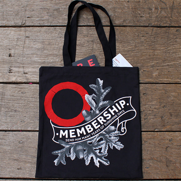 Natural wood flood with black graphic tote bag with Globe membership logo in white and red Globe logo