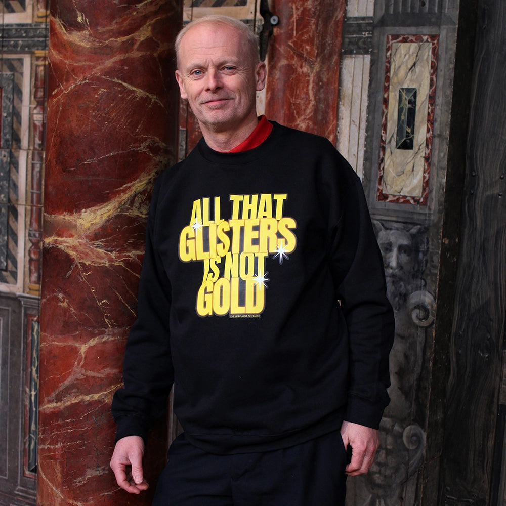 Black matt sweatshirt with gold text graphic in stylised text on man, leaning against column on Globe stage