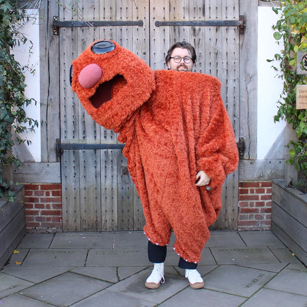 
                  
                    Burnt orange monster costume with oversized head
                  
                