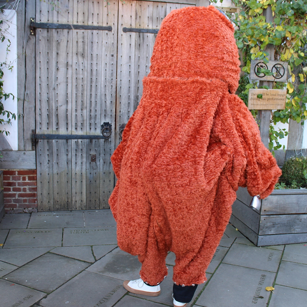 
                  
                    Burnt orange monster costume with oversized head
                  
                