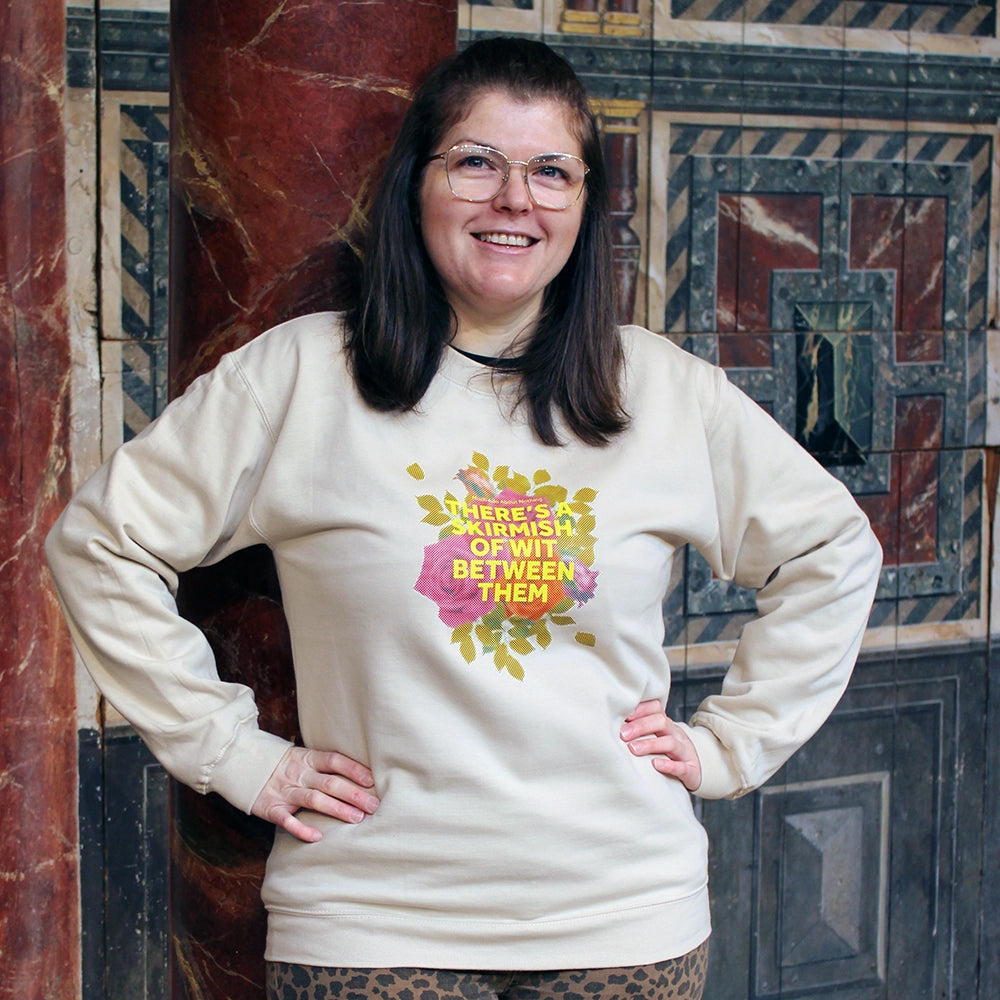 Sand coloured sweatshirt with pixelated image of roses with yellow graphic text overlayed, on female model