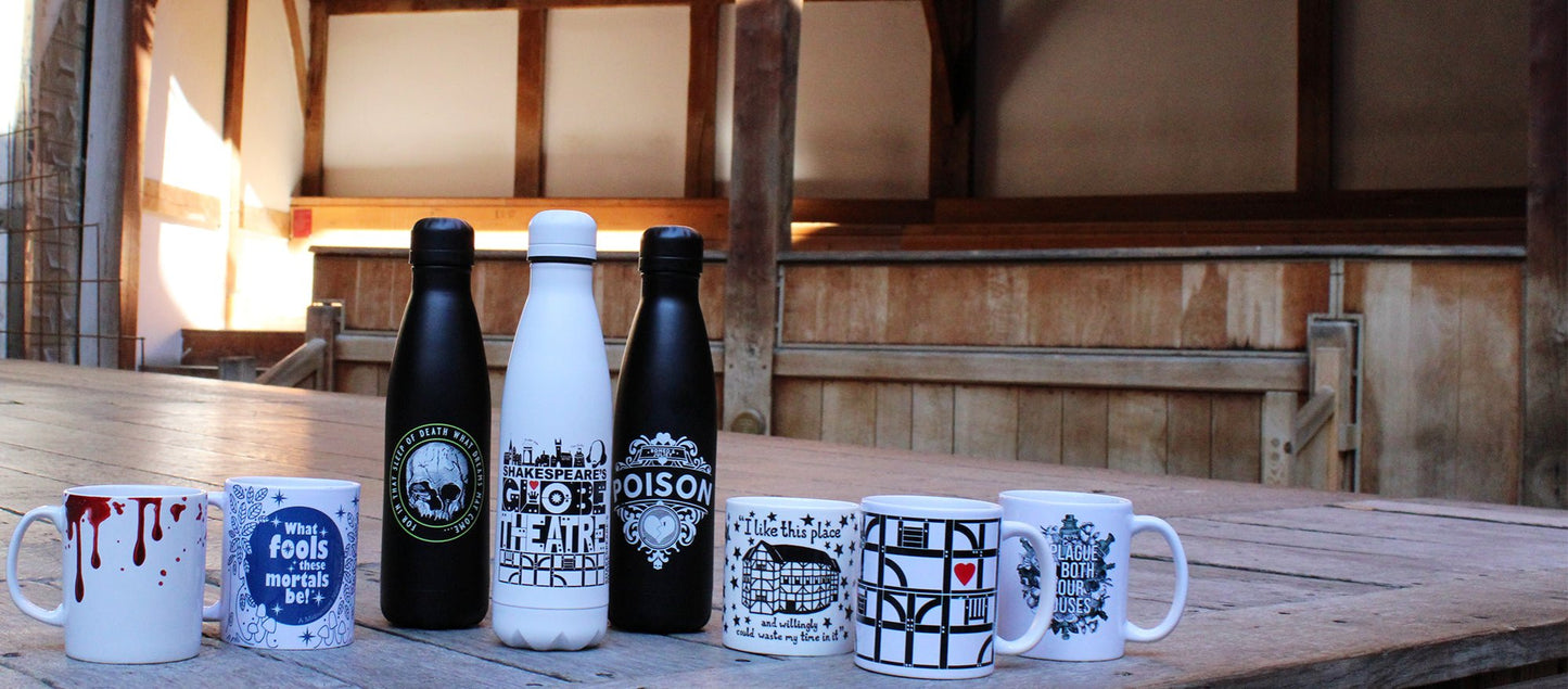 Shakespeare themed white mugs with graphic prints and white and black drinks bottles with graphic prints sitting on wood panel Globe stage