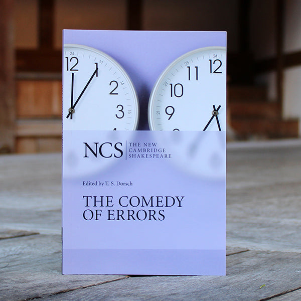 
                  
                    Lilac coloured paperback book with two clocks on cover and black text
                  
                