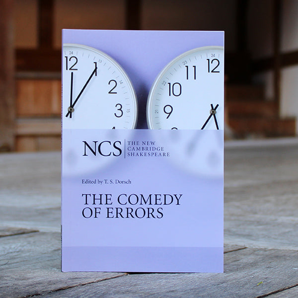 Lilac coloured paperback book with two clocks on cover and black text