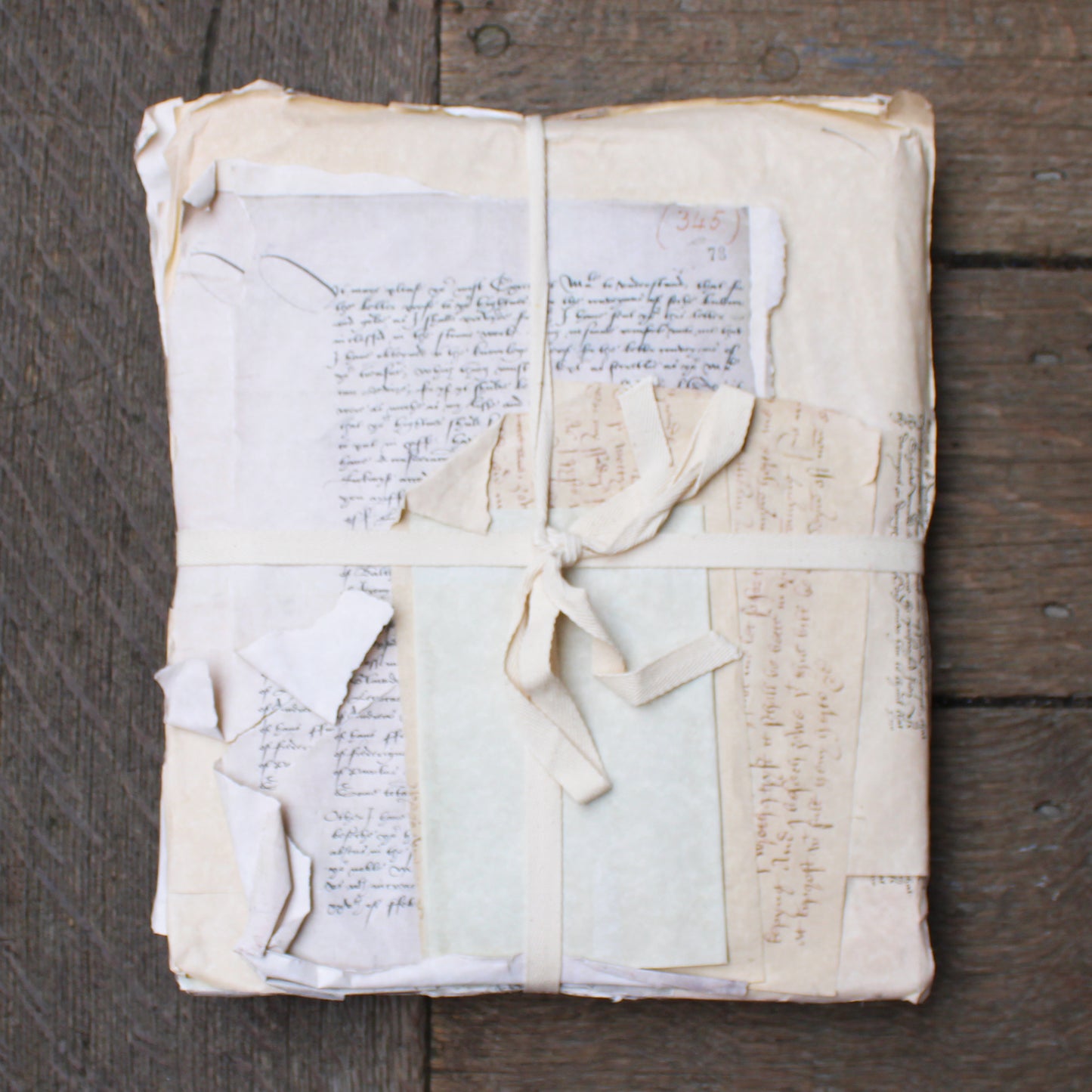Old documents wrapped in white paper with a bow on a wooden surface