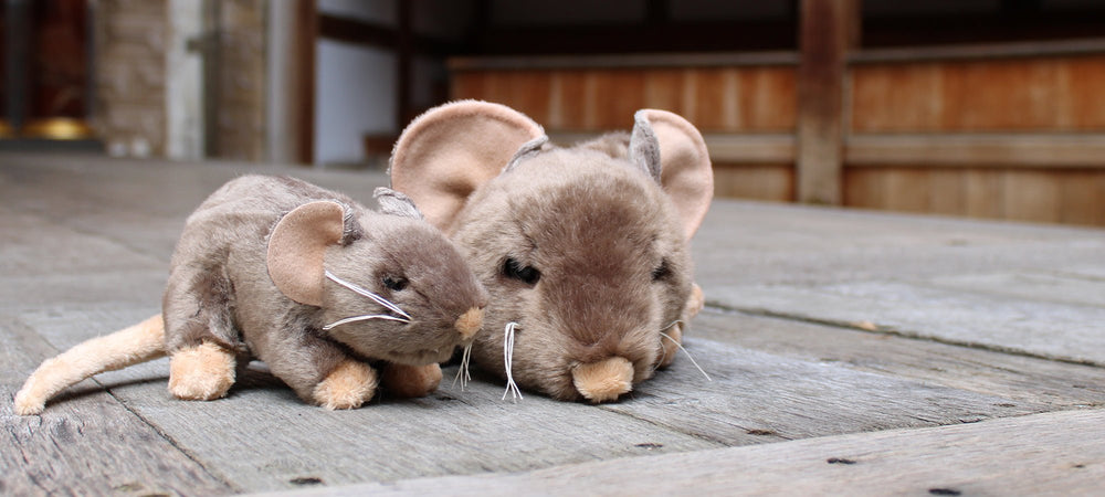 Wood panel stage with 2 beige rat toys, smaller rat plushie in foreground and larger rat puppet to its right