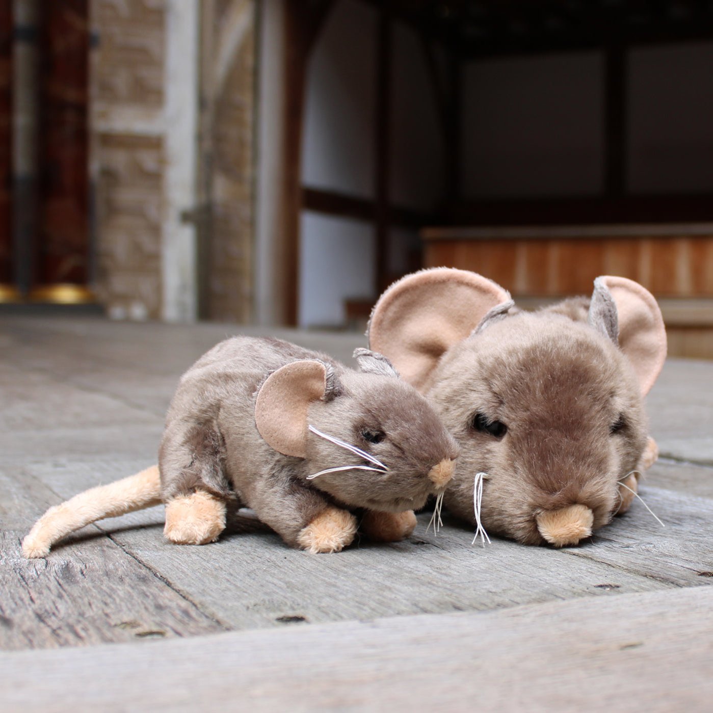 Two beige/brown stuffed rat toys with long beige tails and white whiskers, sitting on the Globe stage