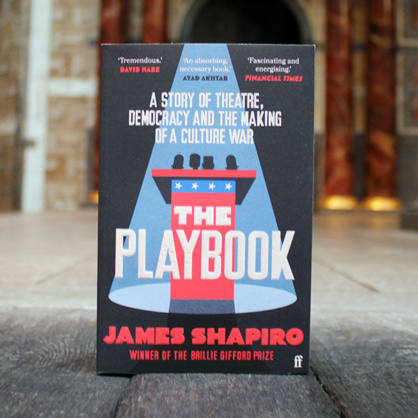 A book titled 'The Playbook' by James Shapiro standing on a wooden surface
