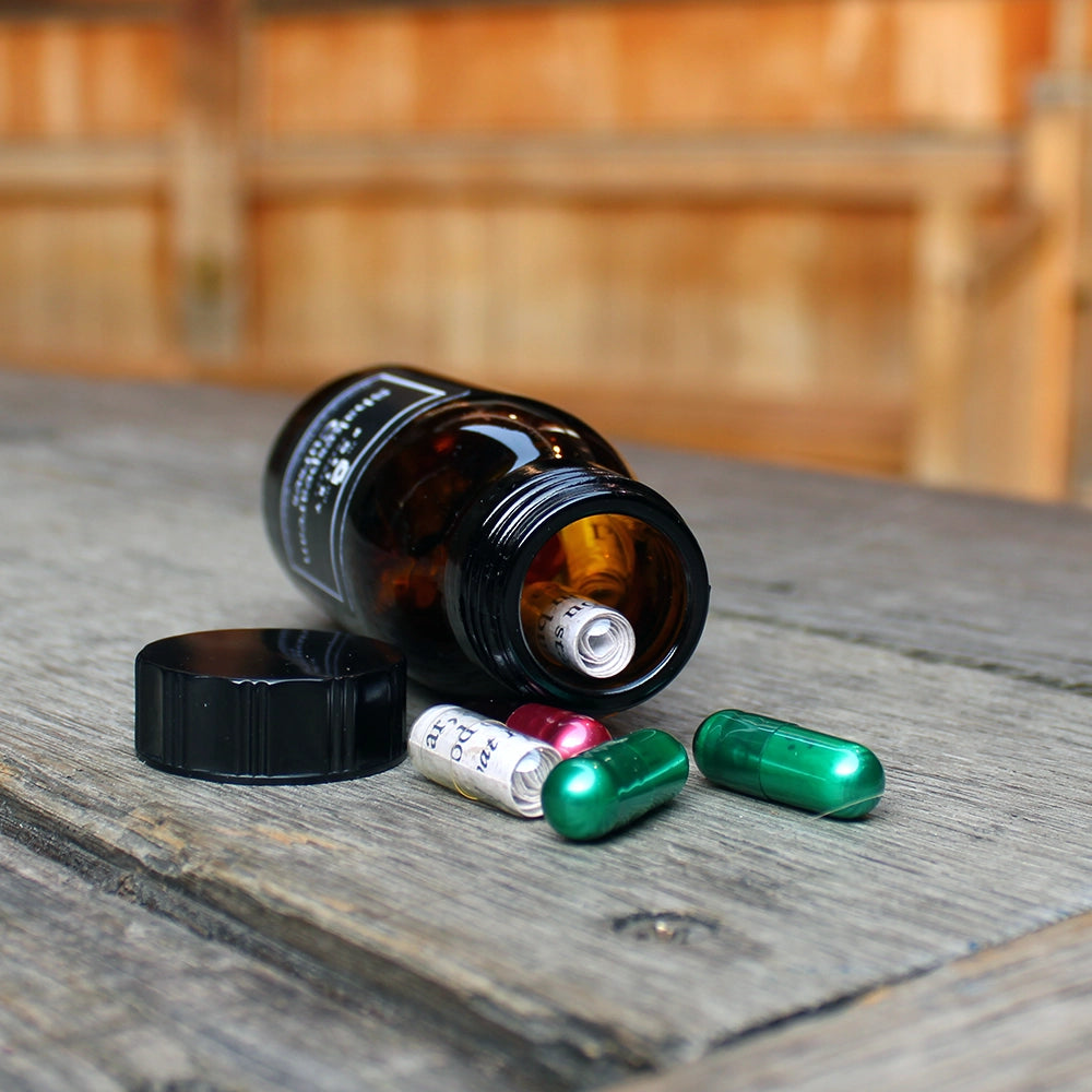 
                      
                        Brown pill bottle with black lid and black label with white writing on it, filled with multicoloured pill poems
                      
                    