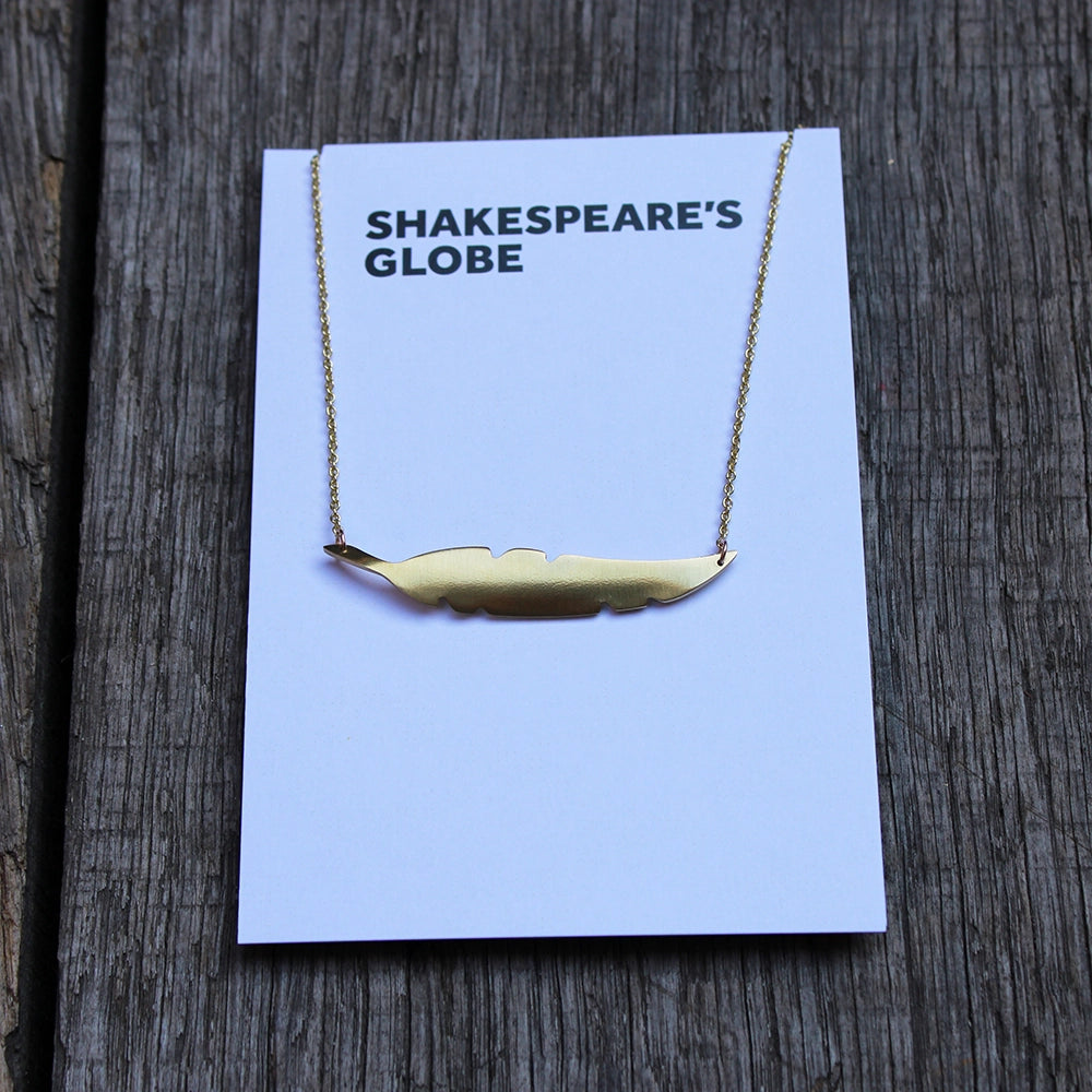 
                      
                        brass metal quill shaped necklace with a gold coloured chain, on white branded backing card
                      
                    