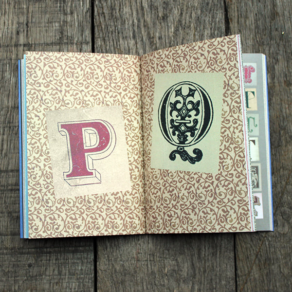 Open book with decorative stickers featuring a letter 'P' and a black design on a wooden surface