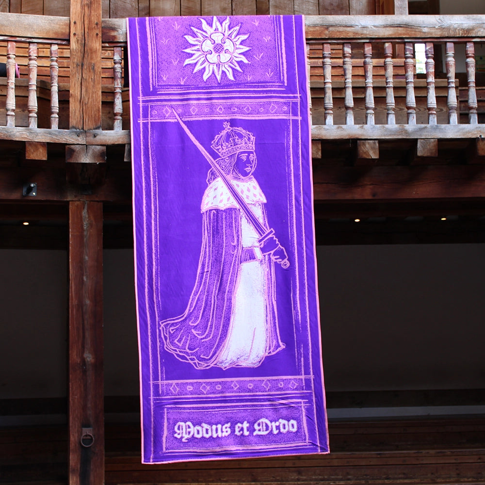 Deep purple fabric banner with white and pink graphics, hanging from wooden rafters