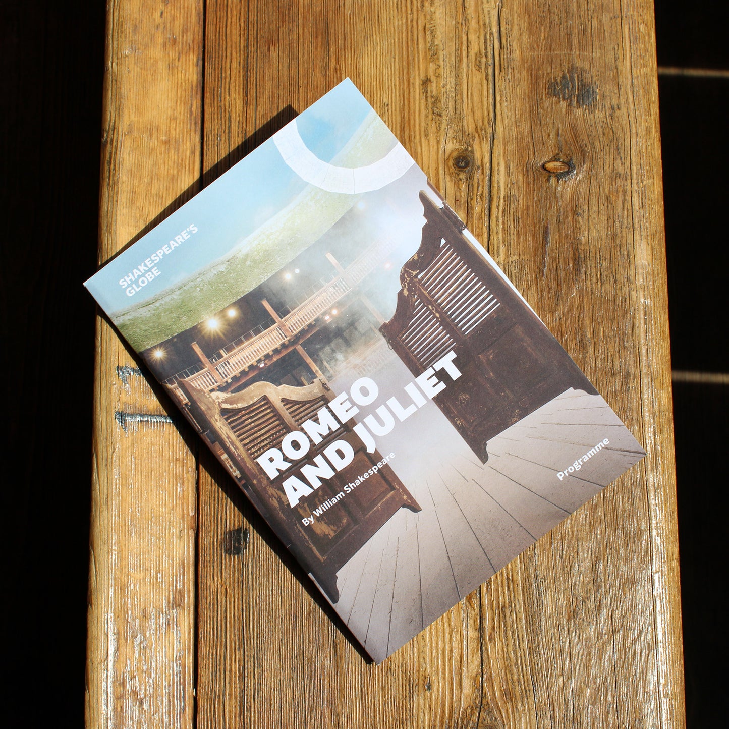theatre programme with a photographic cover lying on a wooden bench