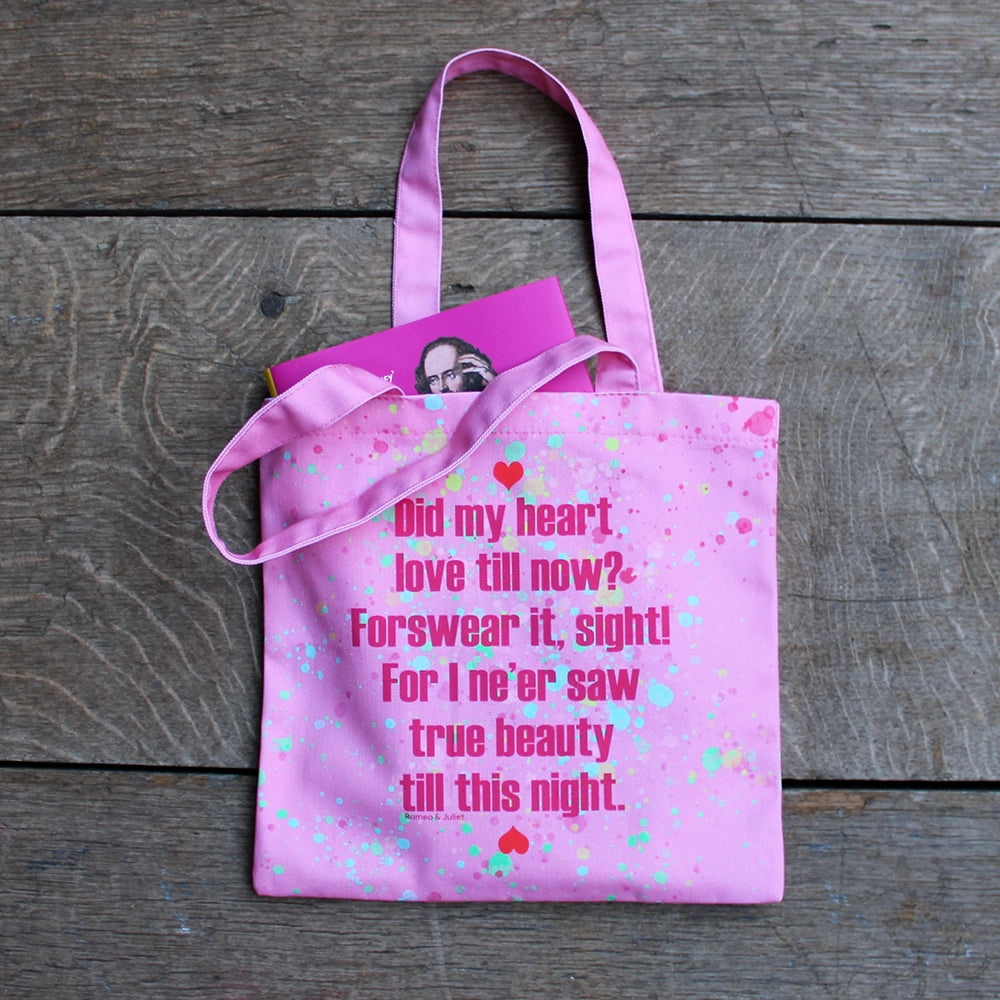 
                      
                        Bubble gum pink tote bag with bright pink writing and yellow, teal and green paint splatter and red hearts, with fuchsia pink book poking out 
                      
                    