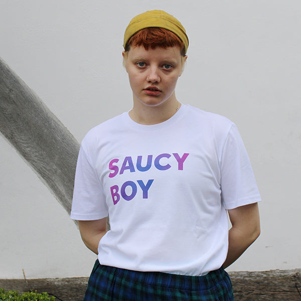 White t-shirt with gradient text purple and blue, two lines of capitalised text reading: SAUCY BOY on model