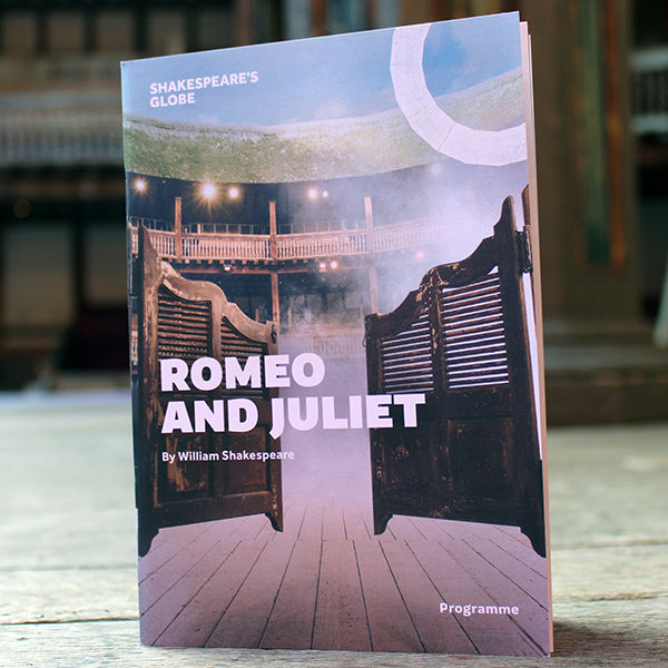 Paper programme on wood stage, programme cover has the Globe with saloon doors on the front