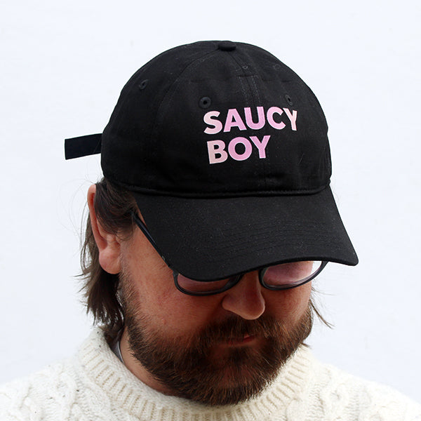 
                  
                    Black baseball cap printed with pink text that reads SAUCY BOY
                  
                