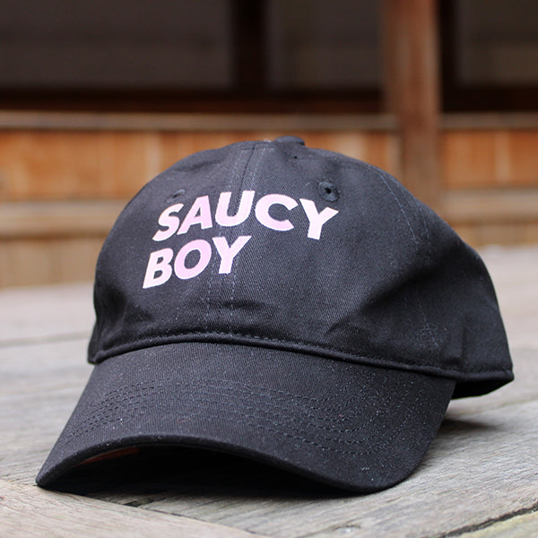 
                  
                    Black baseball cap printed with pink text that reads SAUCY BOY
                  
                