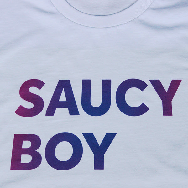 
                  
                    White t-shirt with gradient text purple and blue, two lines of capitalised text reading: SAUCY BOY
                  
                